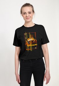 Černé bavlněné tričko s grafickým potiskem kraba, zdobené oranžovými a žlutými akcenty a textem, na vzorovaném pozadí.
