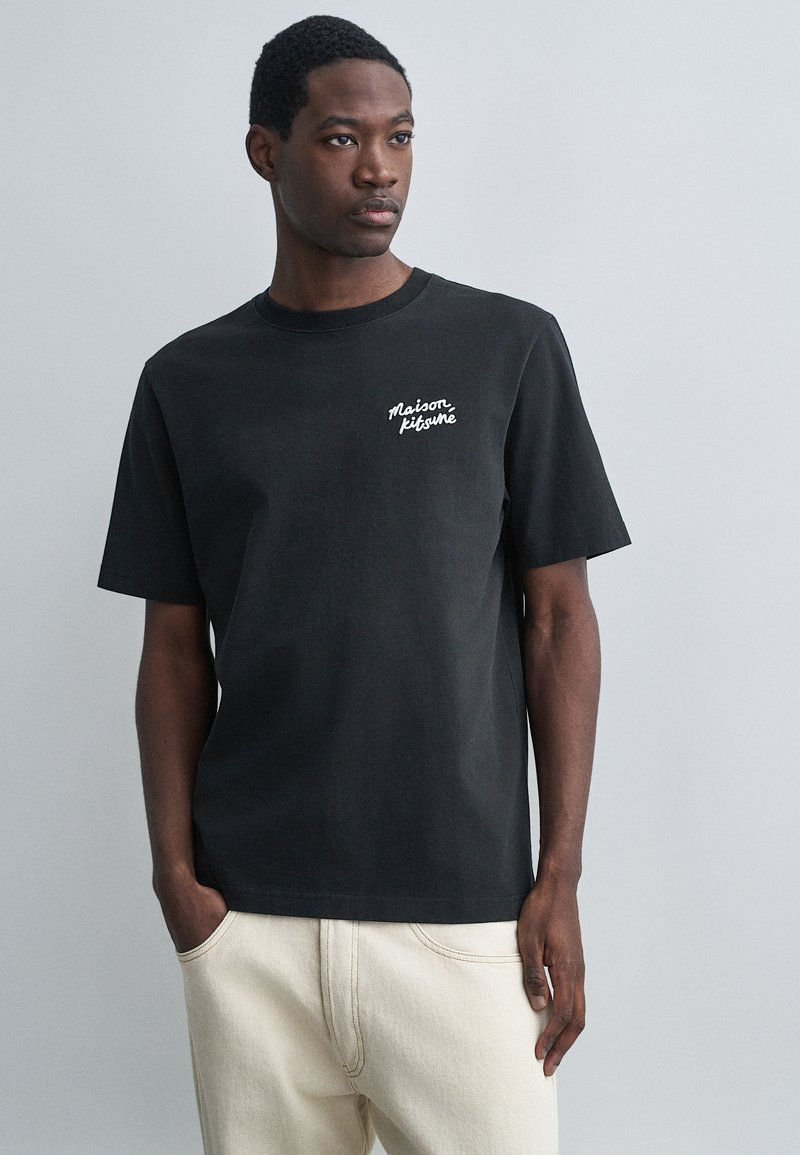 Čierne bavlnené tričko s klasickým výstrihom, krátkymi rukávmi a bielym vyšitým logom "Maison Kitsuné" na ľavej strane hrude.