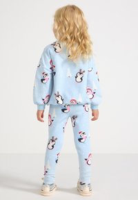 Blue kid's pajama set featuring penguin and snowman patterns. Soft fabric with long sleeves and fitted pants. Light snowflakes throughout.