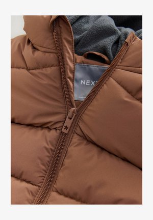 Hnedá bundová pufferka s prešívaným dizajnom, s uzáverom na zips a mäkkou šedou fleecovou podšívkou na golieri. Značková etiketa je viditeľná vo vnútri.