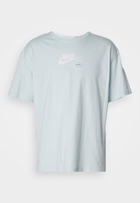 Jasnoniebieska bawełniana koszulka z okrągłym dekoltem i krótkimi rękawami. Na przodzie znajduje się biały logo Nike. Miękka w dotyku.