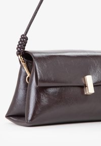 Borsa in pelle marrone scuro con una tracolla annodata e una chiusura rettangolare dorata, mostrata da un angolo frontale su uno sfondo bianco.