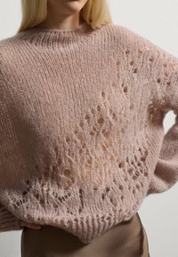 Maglione lavorato a maglia rosa chiaro con vestibilità ampia, caratterizzato da un motivo testurizzato e dettagli a trama aperta, realizzato in un materiale soffice e fluffy.