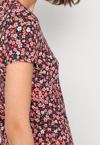 Lyhythihainen mekko tummasta kankaasta, jossa on punaisia, vaaleanpunaisia ja valkoisia kukkakuosisia kuvioita. Mekko on muotoiltu tiukasti ja sillä on sileä pinta.