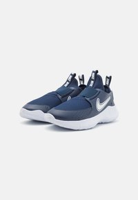 Baskets de sport bleu marine avec des panneaux en mesh, design à bande élastique, semelle blanche contrastante et logo Nike bien en vue sur le côté.