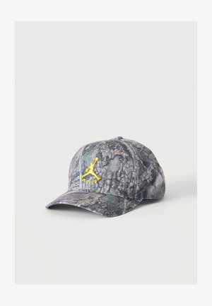 Czapka bejsbolowa w kamuflażowy wzór z żółtym wyszywanym logo Jumpman oraz napisem „Air” z przodu na jednolitym tle.