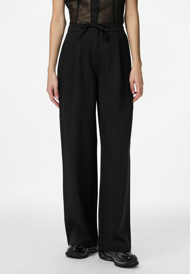 Pantalon large noir à fines rayures, avec une taille à cordon de serrage et une texture lisse. Présente une coupe décontractée et un design élégant.