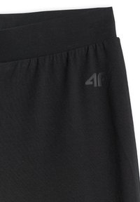 Ceinture élastique noire d'un pantalon de sport avec un logo discret "4F" en haut à droite.