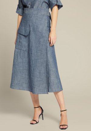 Blaue Denim-Midijupe mit einer seitlichen Tasche, tailliertem Schnitt und gerader Silhouette. Weiche Textur und dezente Webdetails.