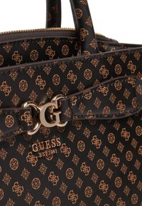 Bolso de mano marrón con patrón y herrajes dorados. Presenta un diseño de monograma y un logo en la parte frontal. El material parece texturizado y sintético.