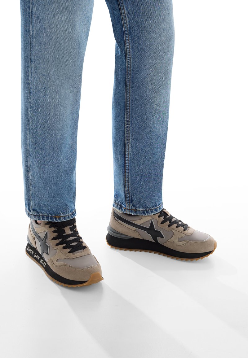 Beige a šedé tenisky s černými akcenty, s texturovaným svrškem, význačným hvězdným logem a gumovou podrážkou s drážkami.