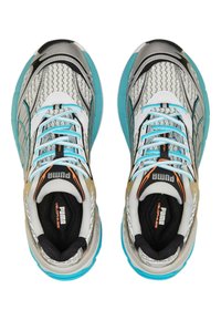 Scarpe da corsa Puma con una tomaia argentata testurizzata, accenti turchesi, suola nera, lacci blu e dettagli con logo sulla linguetta.