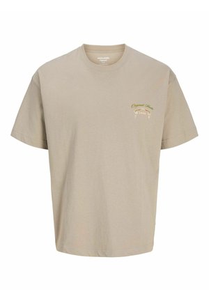 Beež lühikeste varrukatega ümara kaelusega T-särk, millel on vasakul rinnal väike roheline ja valge kiri "Original Since 1990" ning dekoratiivne lint.