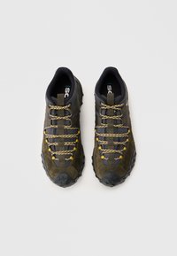 Baskets de sport vert olive et noires avec des semelles texturées et des accents jaunes ; elles présentent un lacet complexe et des cols rembourrés pour le soutien.
