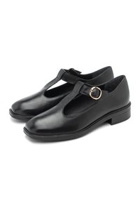 Zwarte leren Mary Jane-schoenen met een ronde neus, T-bar ontwerp en een gouden gespaccent op een lage blokhak. Gladde textuur, geen patronen.