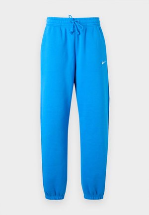 Φωτεινό μπλε φόρμα Nike με ελαστική μέση, ρυθμιζόμενο κορδόνι, ελαστικά τελειώματα και μικρό λευκό λογότυπο Nike στο δεξί μηρό.