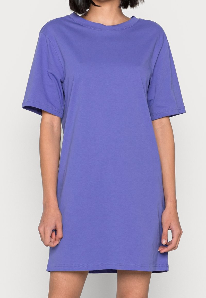 Fioletowa sukienka t-shirt z krótkim rękawem i okrągłym dekoltem, wykonana z gładkiego materiału, charakteryzująca się luźnym krojem i prostym wykończeniem.