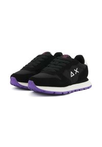 Zwarte sneakers met paarse zolen, witte middentoevoegen, zwarte veters en wit "ΔX" logo aan de zijkanten, weergegeven in een paar op een witte achtergrond.