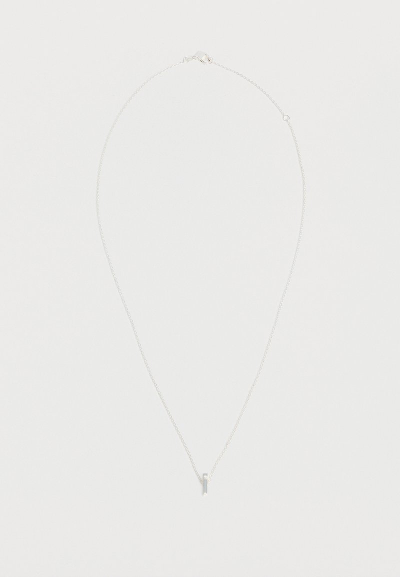 Collier délicat en chaîne argentée avec un petit pendentif barre verticale sur fond blanc.