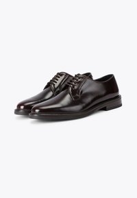 Scarpe eleganti in pelle marrone con finitura lucida, punta tonda, cinque occhielli per i lacci e suola in gomma sottile. Design semplice ed elegante.