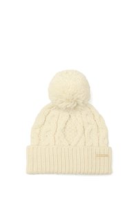 Gorro de invierno color crema, tejido, con patrón de trenzas, gran pompón en la parte superior y un borde de canalé doblado con una pequeña etiqueta de marca.