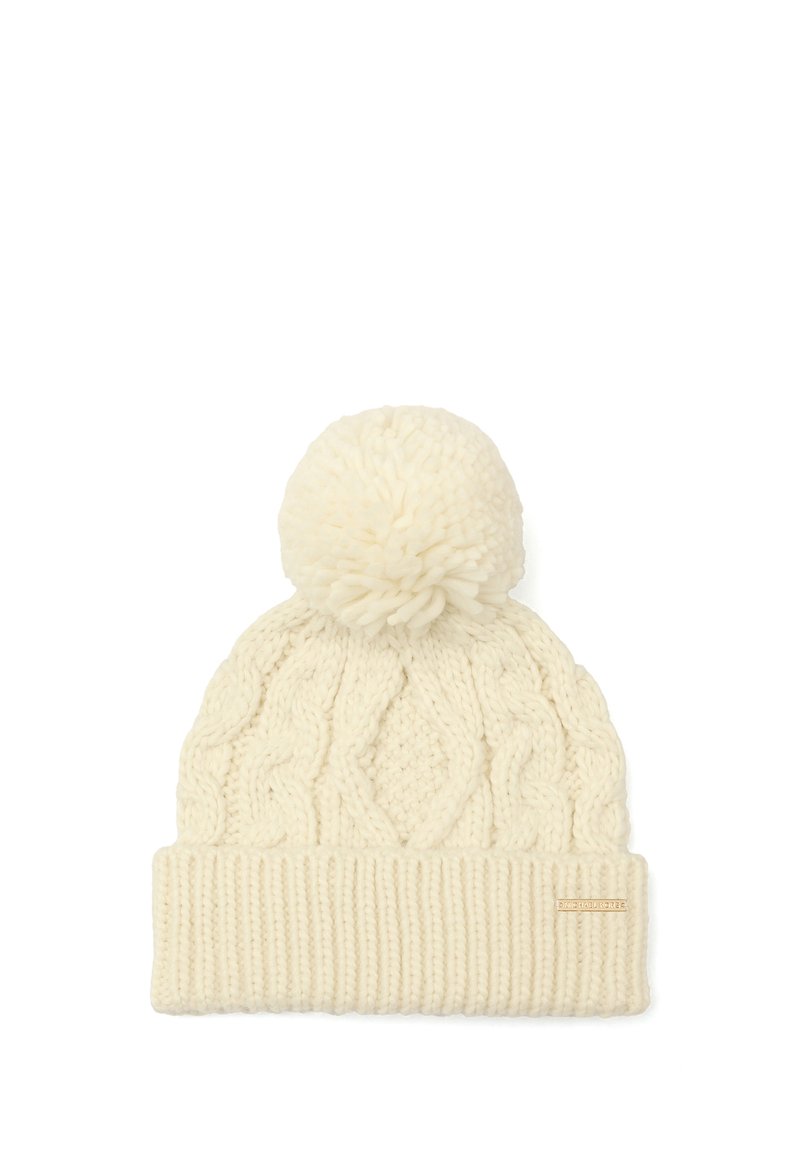 Gorro de invierno color crema, tejido, con patrón de trenzas, gran pompón en la parte superior y un borde de canalé doblado con una pequeña etiqueta de marca.