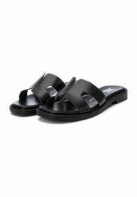 Sandalias negras de slide con dos correas curvas, que presentan secciones recortadas. Están fabricadas de un material sintético suave con una suela plana.
