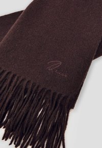 Brūns vilnas šalle ar frizētām malām un smalku tekstūru, ar izšūtu logotipu gaišākā tonī.