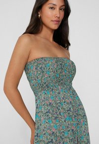 Vestido maxi sin mangas de flores en verde con patrones de paisley en azul, rosa y púrpura. Cuerpo fruncido y detalle de falda fluida.