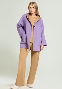 Lila wollen blend jas met een capuchon, zwarte knopen, twee zakken en een beige top en broek, met een soepele textuur en een relaxte pasvorm.