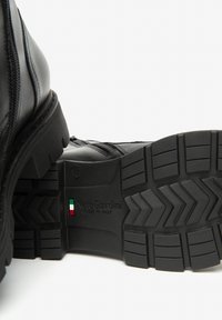 Stivale alla caviglia in pelle nera con zip laterale, suola in gomma testurizzata con profili profondi e logo impresso sul tallone. Made in Italy.