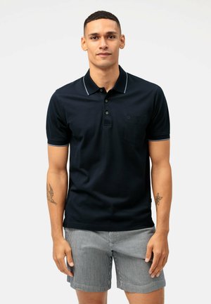 Marineblaues Poloshirt mit drei Knöpfen, kontrastierendem Kragen und Streifen an den Ärmeln sowie einer Brusttasche. Kurze Ärmel und weicher Stoff.