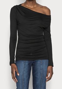 Sort langærmet top med off-shoulder design, prydet med samlet tekstur, blødt stof og uden sømme, parret med denim bukser.