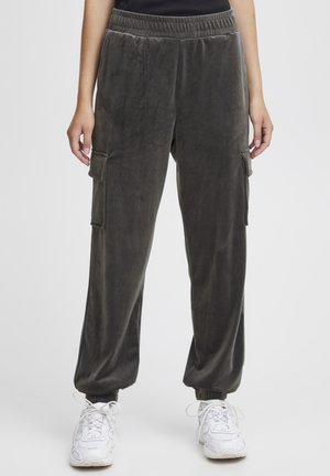 Mörkgrå sammet joggers med elastisk midja, sidofickor och avsmalnande ärmar. Mjuk textur och avslappnad passform.
