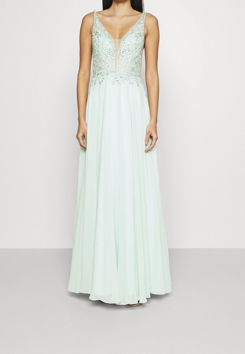 Dlouhé mátově zelené večerní šaty s výstřihem do V a zdobeným živůtkem. Obsahují volnou sukni a složité korálkování podél výstřihu.