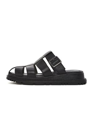 Sandalo in pelle nera con punta aperta, design a più cinghie, una fibbia laterale e una suola in gomma nera testurizzata. Presenta un profilo piatto.