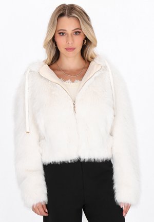 Witte nepbontrandcropped jas met een capuchon, voorzien van een voorkleurige ritssluiting, trekkoorden en een zachte textuur. Gepaard met een lichtgekleurde top en zwarte broek.