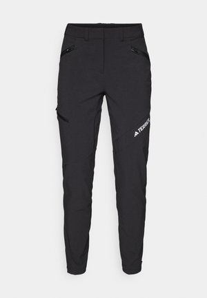 Black outdoor pants feature a slim fit, zippered pockets, reinforced knees, and a logo on the left side. Made from durable, lightweight fabric.