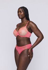 Koronkowy zestaw bielizny w kolorze koralowym, składający się z biustonosza z koronkowymi akcentami oraz siateczkowymi miseczkami, dopasowanych majtek, ukazujący gładką teksturę i skomplikowane wzory.