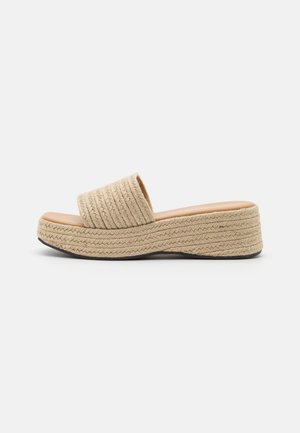 Beige vævet platform klip sandal med bred rem og tekstureret sål, vist fra siden på hvid baggrund.