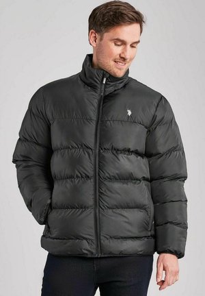 Musthave musta puffjakker kõrge kraega, tikandiga disain ja diskreetne logo. Omab tõmbluku sulgemist ja siledat, läikivat kangast.
