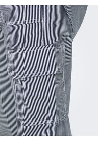 Gros plan d'un pantalon à rayures verticales bleu marine et blanc avec une poche à rabat sur la cuisse côté sur un fond clair uni.