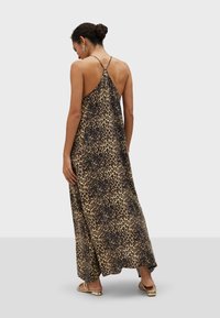 Robe maxi à imprimé léopard avec un col halter, présentant une silhouette fluide et un tissu doux. Accentuée de fines bretelles et d'un détail au dos.