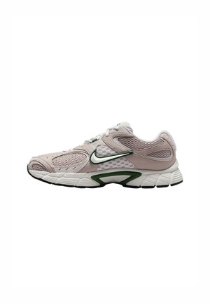 Zapatilla deportiva de color rosa claro con paneles de malla, acentos verdes y una suela de goma texturizada. Cuenta con un diseño curvado y una zona de puntera reforzada.