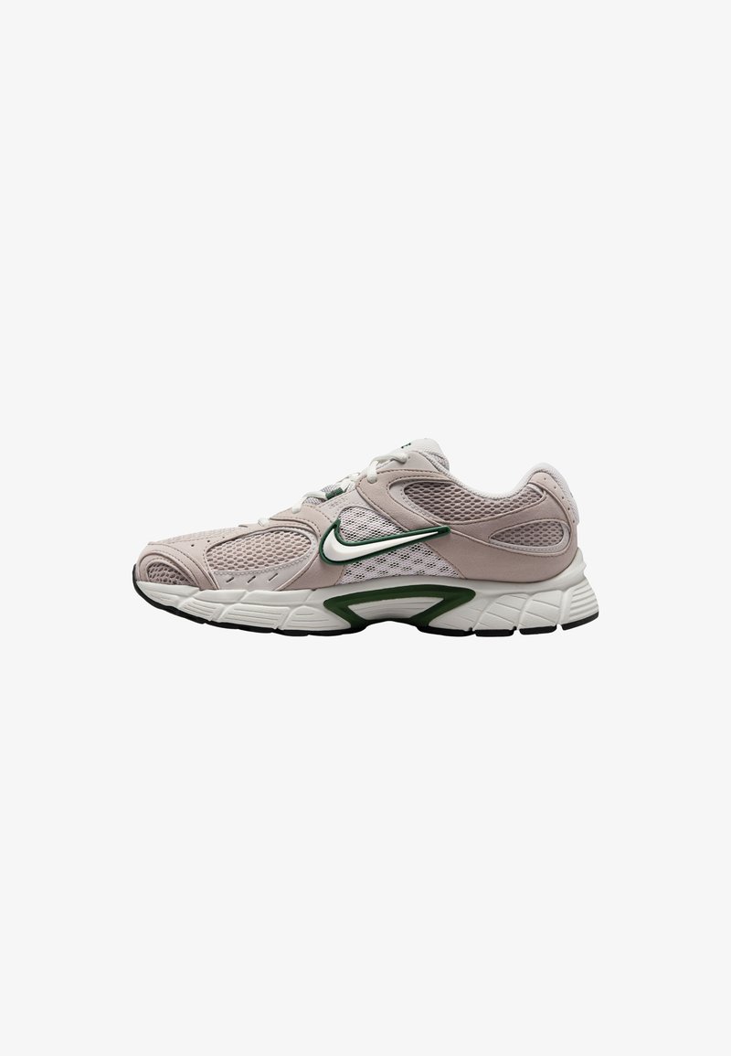 Zapatilla deportiva de color rosa claro con paneles de malla, acentos verdes y una suela de goma texturizada. Cuenta con un diseño curvado y una zona de puntera reforzada.
