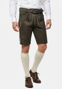 Brune lædershorts med dekorativ gul søm og blomster mønstre, parret med strukturerede cremefarvede knæstrømper og brune sko.