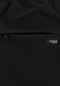 Schwarzer Stoff mit einer zerknitterten Textur, versehen mit einer Reißverschlusstasche und einem Etikett, auf dem "spitzbub STUDIOS" steht. Einfaches Design ohne sichtbare Muster.