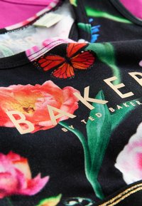 Cvetna črna majica brez rokavov z živahnimi rožnatimi cvetovi, poudarkom v obliki metulja in metalno zlatim logotipom "BAKER". Gladka tekstura in prilegajoča zasnova.