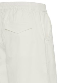 Pantalon blanc à taille élastique montrant une poche arrière avec rabat et une poche latérale dans la couture, présenté sur fond blanc.