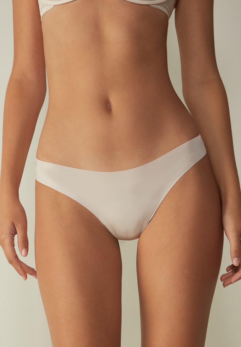 Beige sömlös bikini med låg midja. Slät tyg utan synliga sömmar, vilket ger minimal täckning och en smickrande silhuett.